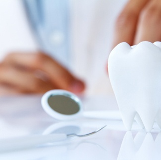 Model of tooth and dental mirror on table