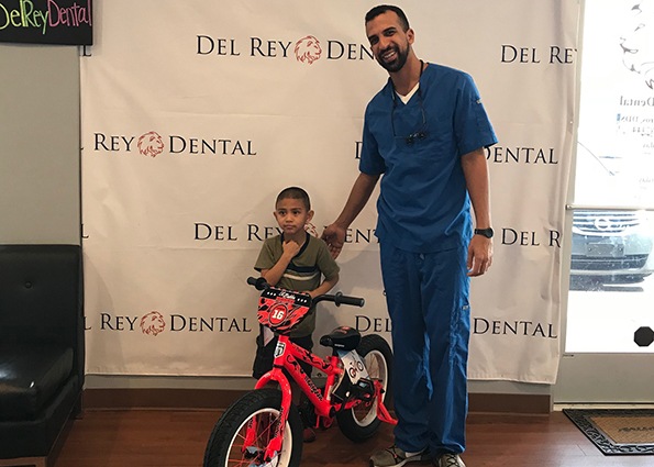 Dr. Tadros posing with young patient and his bicycle