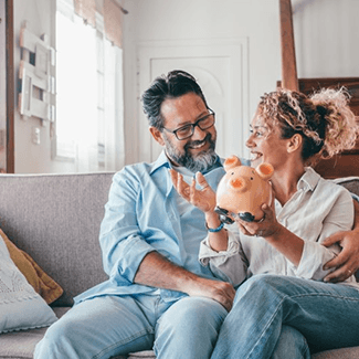 a couple smiling and holding a piggy bank