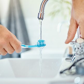 a person putting water on their toothbrush