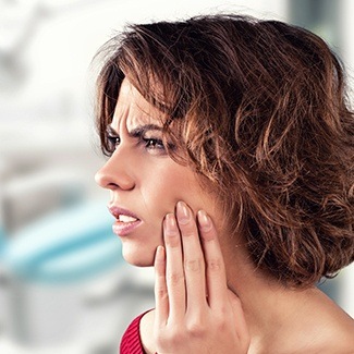 Woman holding cheek in pain from a dental emergency