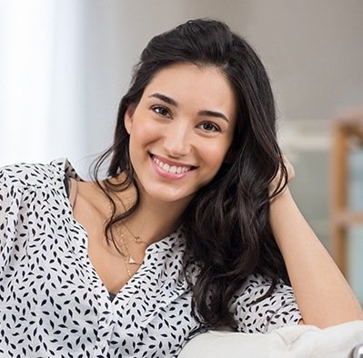 Woman with long dark hair wearing black and white shirt smiling