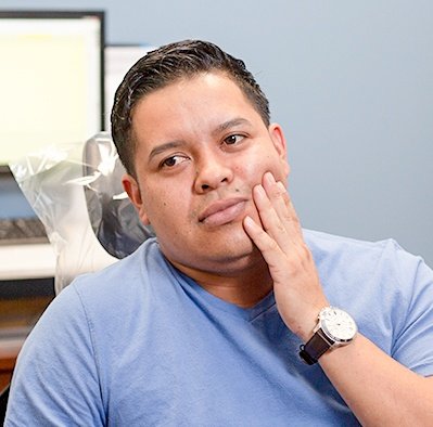 Man in dental chair showing mouth in pain