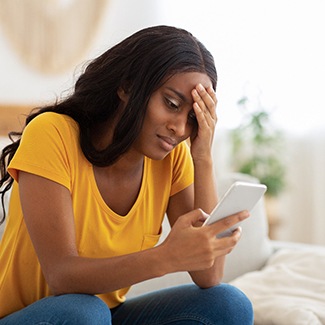 a stressed person trying to find an emergency dentist in Dallas by searching on their phone