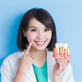 Dentist holding model of dental implants in Dallas