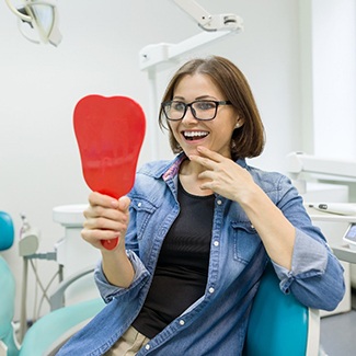 Young woman admiring her new dental implants in Dallas