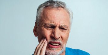 Man rubbing his aching jaw