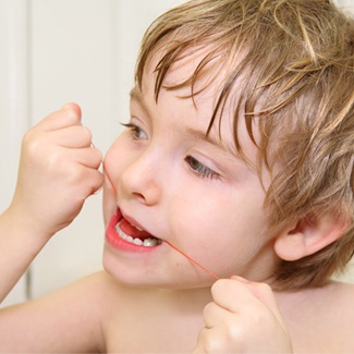 Little boy flossing teeth