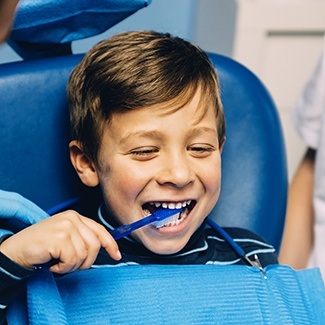 Young boy brushing his teeth while visiting children's dentist in Dallas