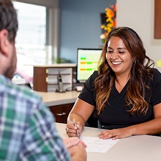 Del Rey office manager, Esme helping dental patient with forms