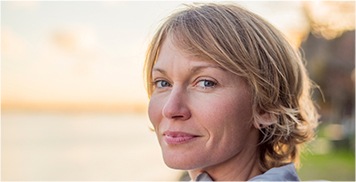 close up of smiling woman with short blonde hair at the beach