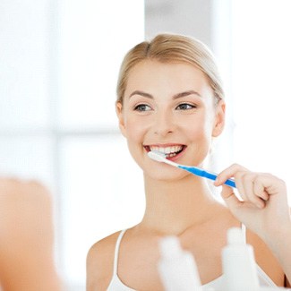 Woman looking in mirror to brush her teeth