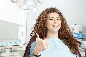 Female dental patient giving a thumbs up