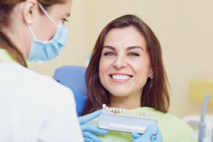 Patient smiling brightly as dentist color-matches their dental implants